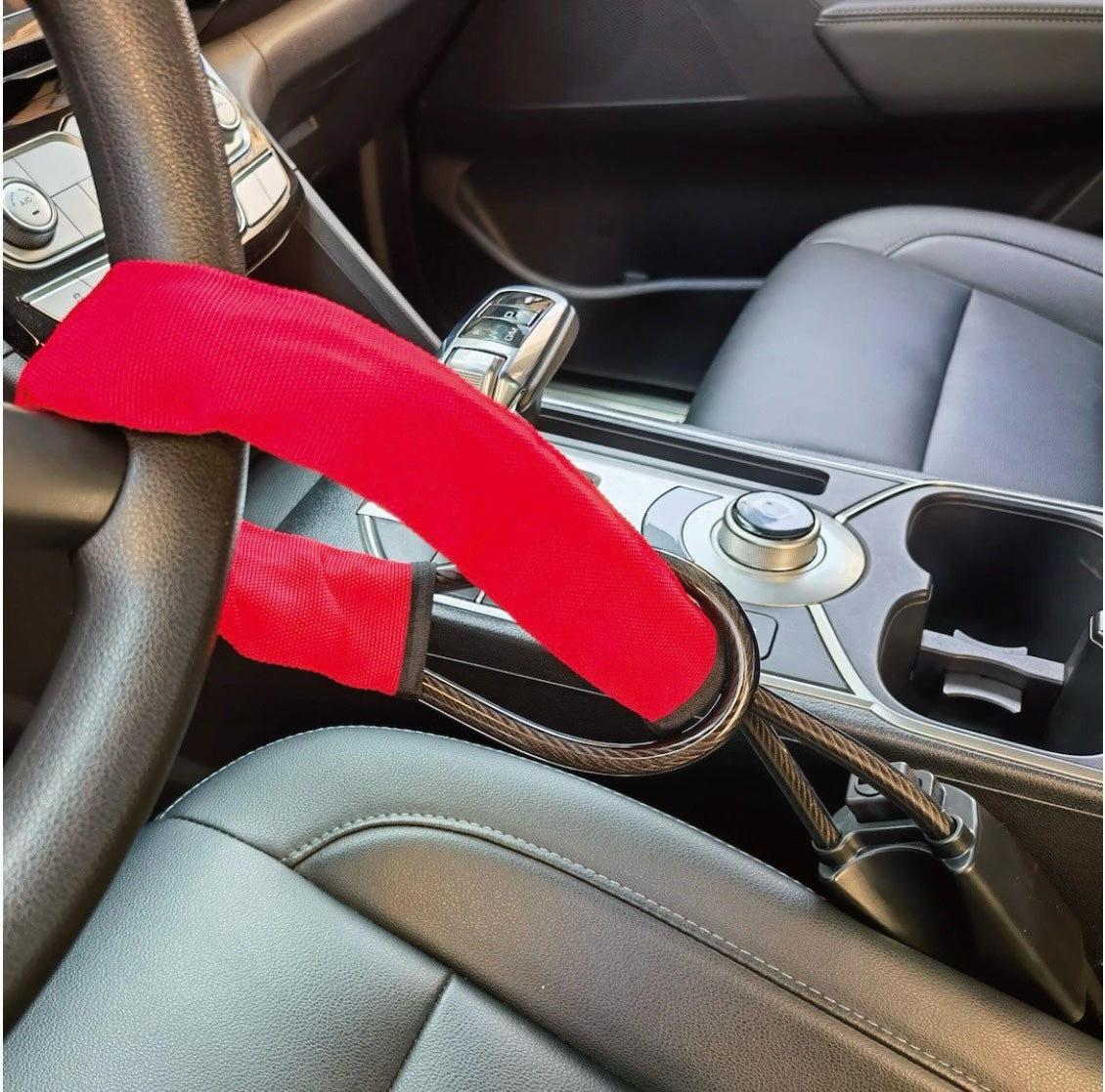 KMD MarketHub red fabric-covered steel cable steering wheel anti-theft lock installed in a car interior