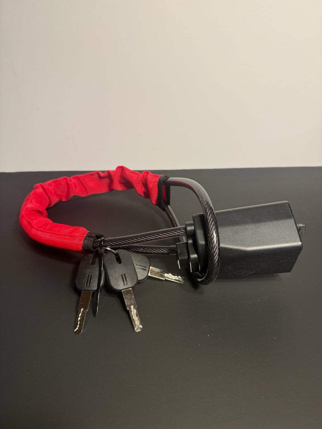 KMD MarketHub red fabric-covered steel cable steering wheel anti-theft lock with four keys on a black surface