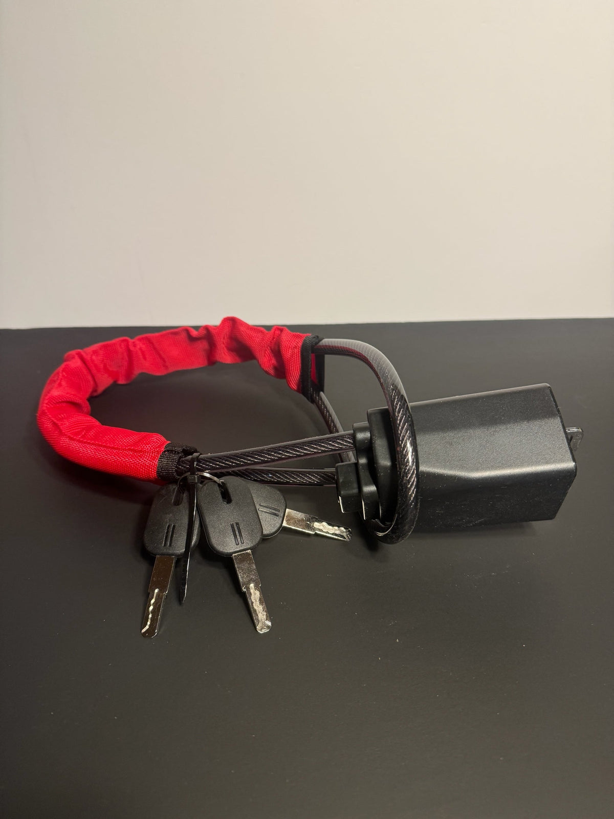 KMD MarketHub red fabric-covered steel cable steering wheel anti-theft lock with four keys on a black surface